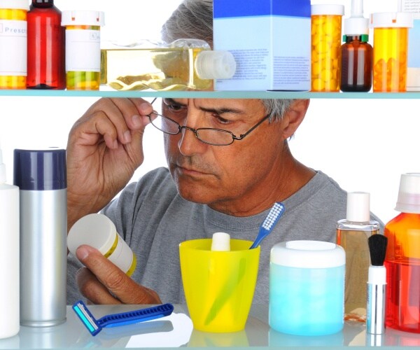 man looking in medicine cabinet