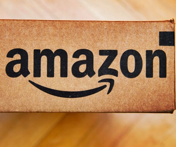 amazon logotype printed on cardboard box side, seen from above on a wooden floor. 