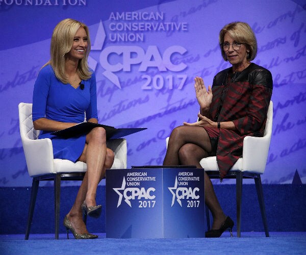 kayleigh mc enany in a blue dress on left, is shown with betsy devos