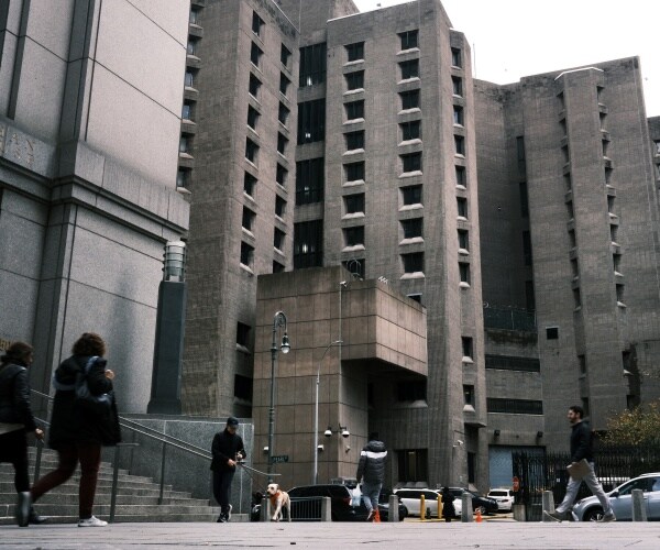 gray federal prison building with people in coats walking near it 