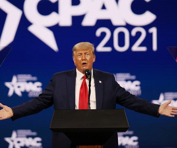 donald trump holds arms out onstage at cpac