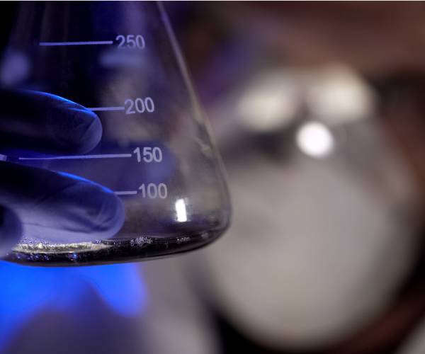 chemist in darkened lab holding a beaker