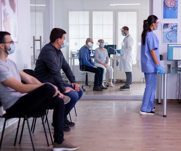 patients in waiting room at hospital wearing surgical masks