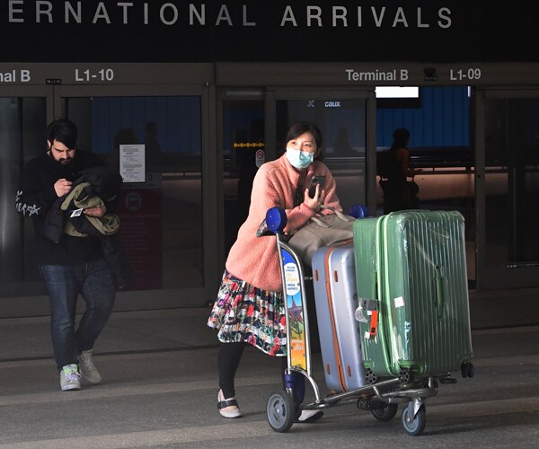 a woman wears a face mask at los angeles international airport