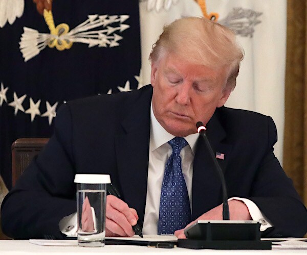 president donald trump signs a bill at the resolute desk