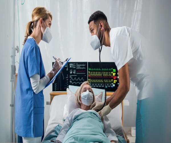 Patient in hospital in bed with a male and female doctor discussing her case