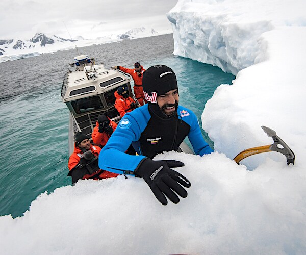 a cliff diving athlete climbs a giant iceberg in antarctica