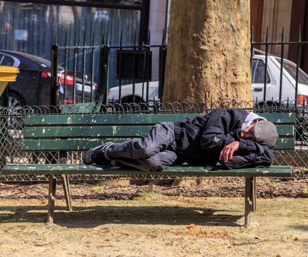 homeless man sleeps on bench