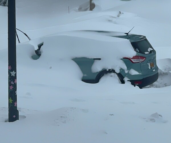 a car sits immobile and blanketed in snow