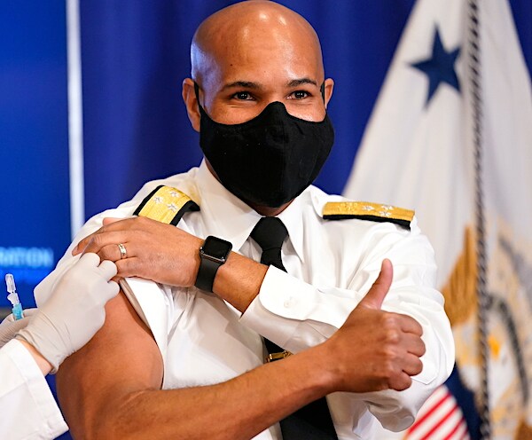 surgeon general jerome adams gives a thumbs up while being vaccinated