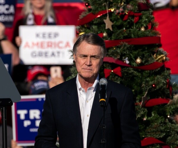 david purdue stands on stage at a rally