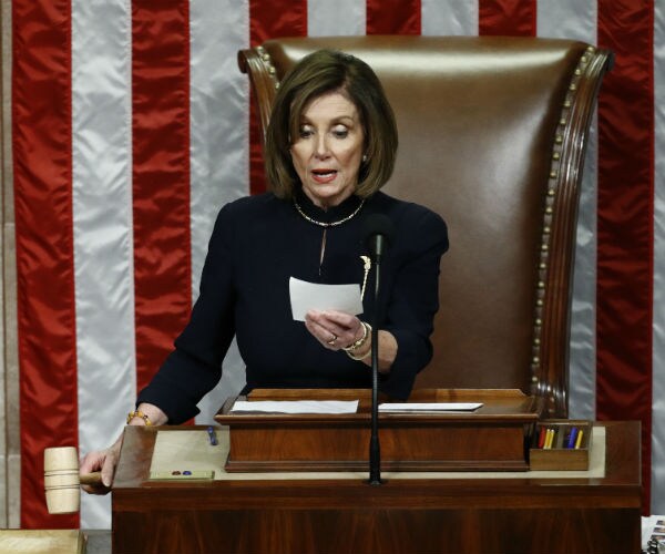 Nancy Pelosi in a blue suit readies to strike the gavel as she announces the passage of article II of impeachment. 