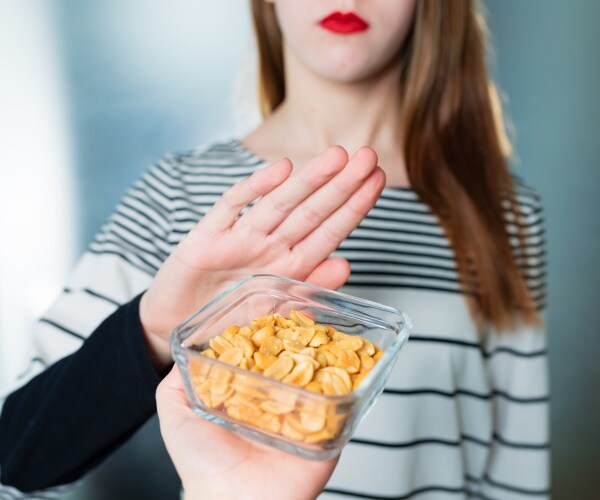 teen girl holds up hand to a bowl of peanuts