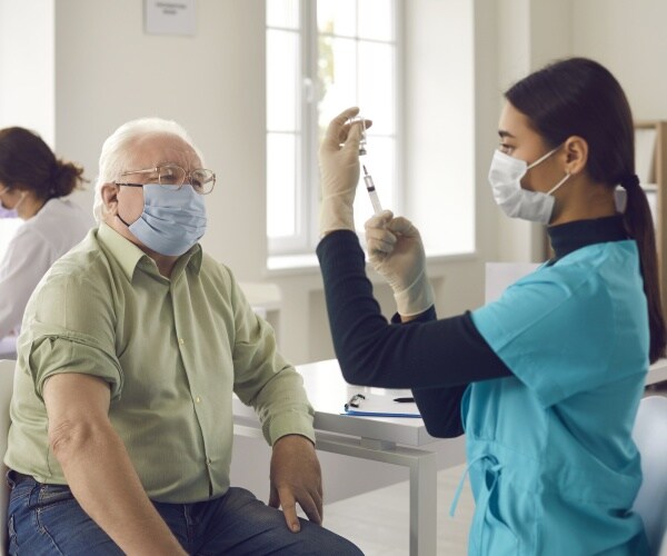 elderly man about to get a vaccine from a doctor or nurse