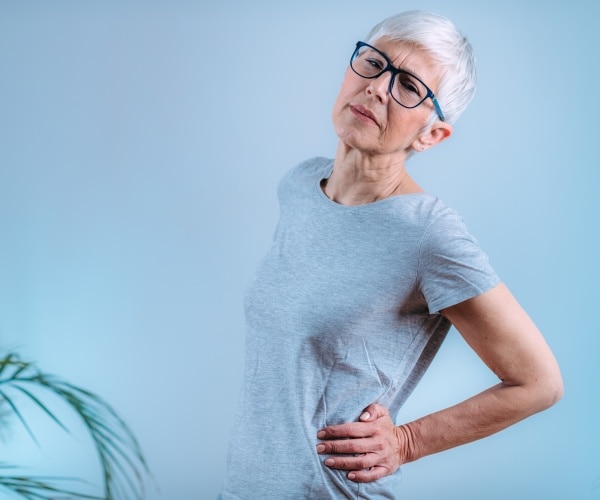 woman with hand on lower back feeling sciatic pain