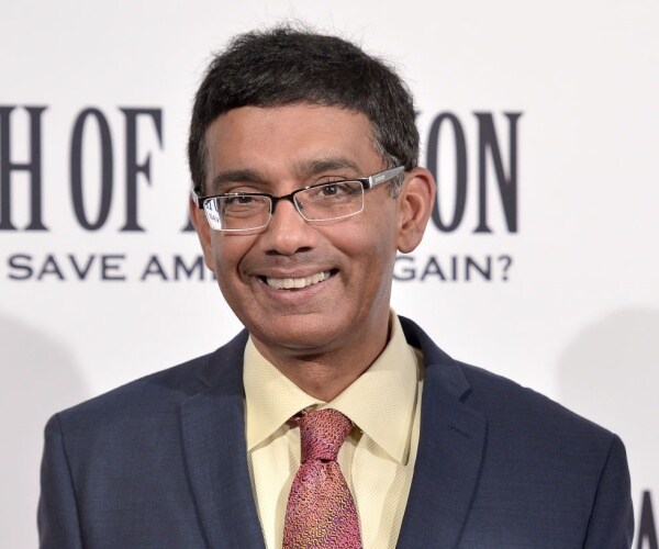 dinesh d'souza with glasses, dark suit, yellow shirt and red tie