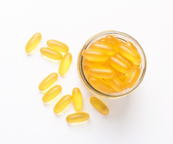 fish oil supplements in a small bowl, on wood table