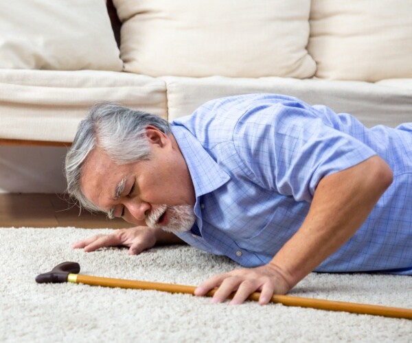 an older man laying on floor with his cane next to him after a fall