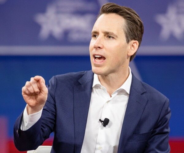 josh hawley in a white shirt and blue blazer speaking at cpac