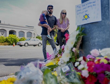 a man, woman and small child near a makeshift memorial