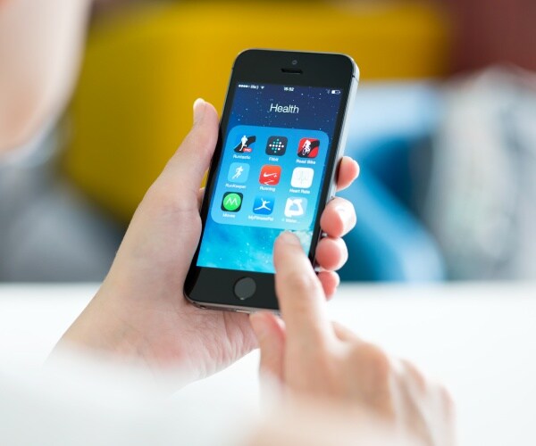 person holding smartphone, heading says 'health' and there are health apps on screen