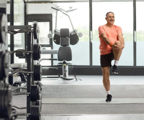 older man doing leg exercises at gym