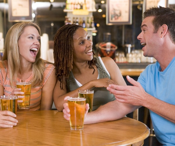 a group of friends laughing and drinking at a bar