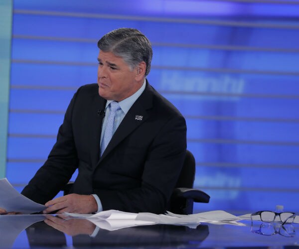 sean hannity sitting behind news desk