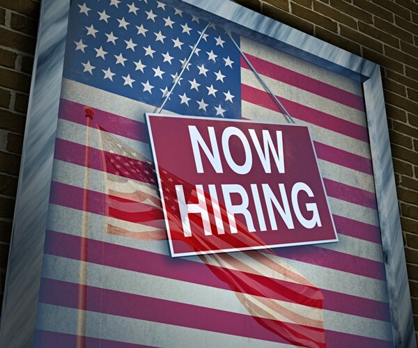 now hiring sign hanging in front of american flag