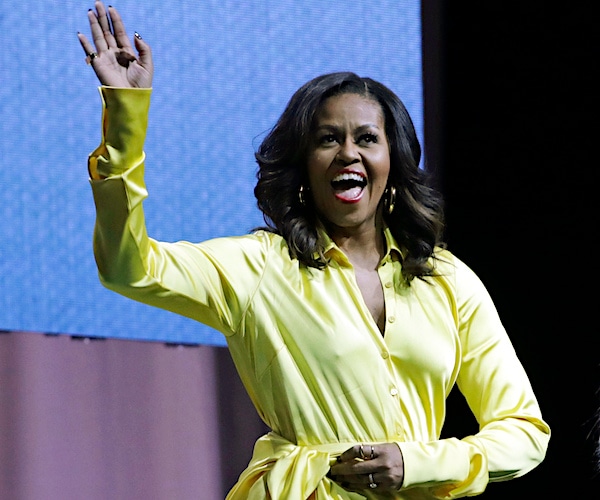 michelle obama waves and smiles on stage at a conference