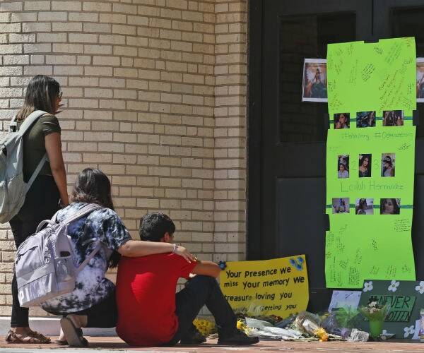 three students gather at a memorial for a slain student in texas