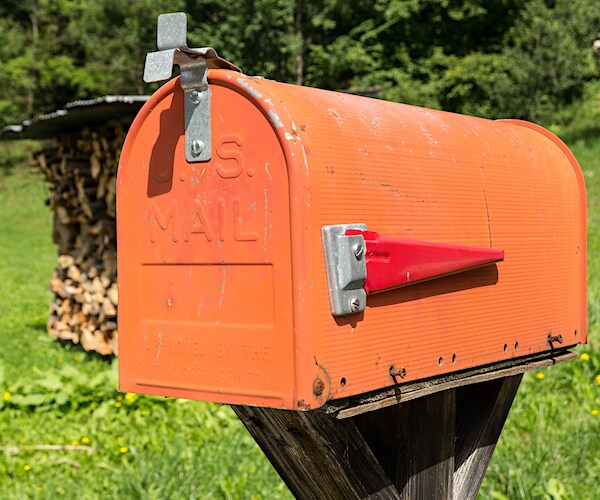 an orange mailbox with a red flag