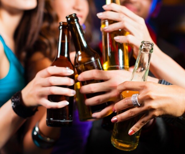 women out at a bar holding their drinks up to cheer