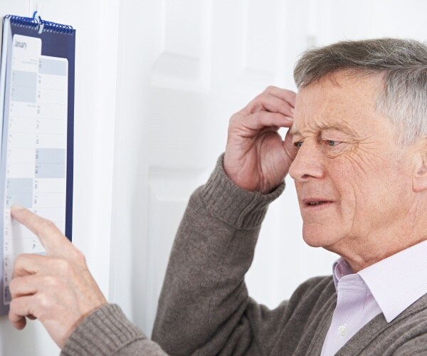 older man looking confused while looking at his calendar on the wall