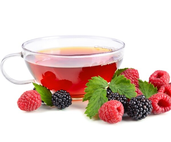 cup of tea in glass teacup, with blueberries and strawberries around it