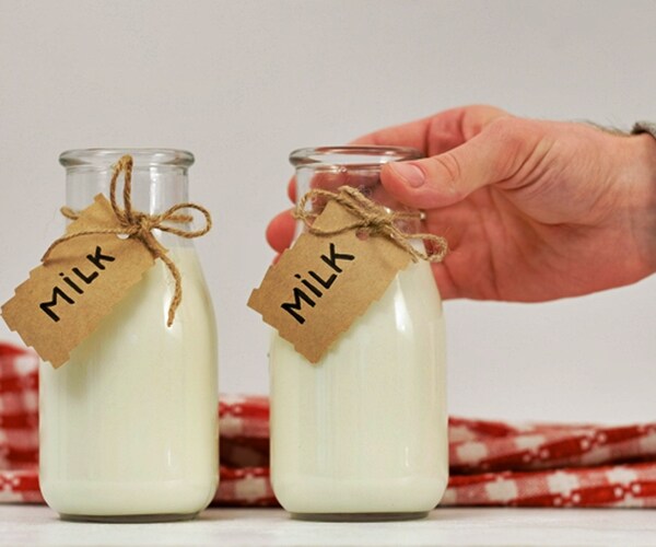  milk and healthy dairy products with two glass bottles with milk tags and hand reaching for them