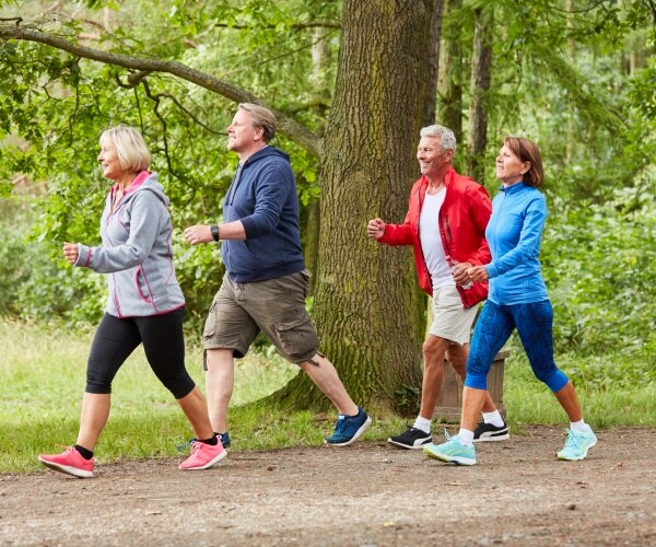 two men and two women walking in park for fitness