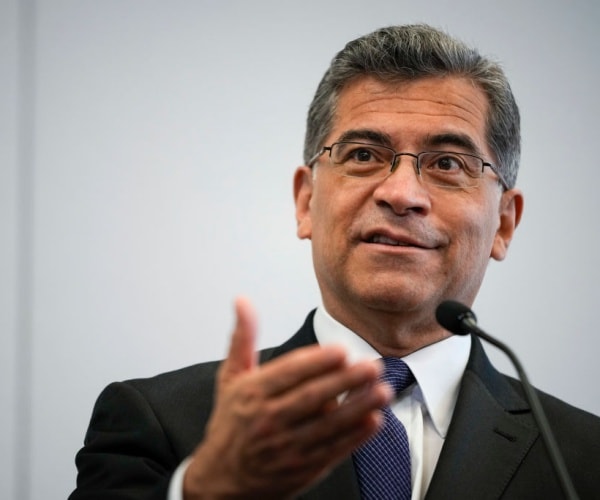 Xavier Becerra gestures while speaking into a microphone