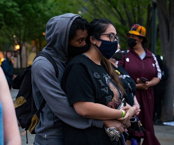 man stands with arms around woman in street