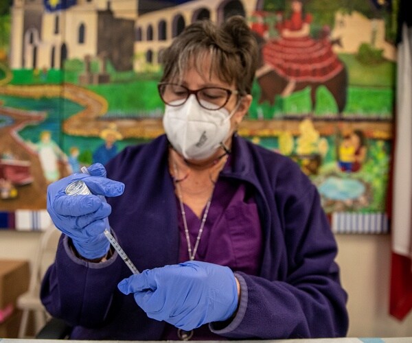 nurse fills a syringe with vaccine