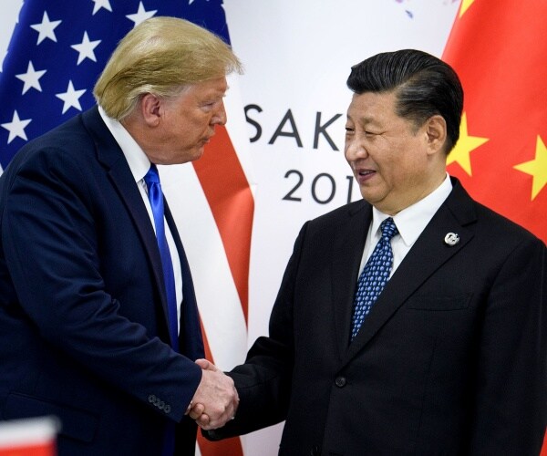 trump and xi wearing suits and blue ties shake hands in front of us and chinese flags