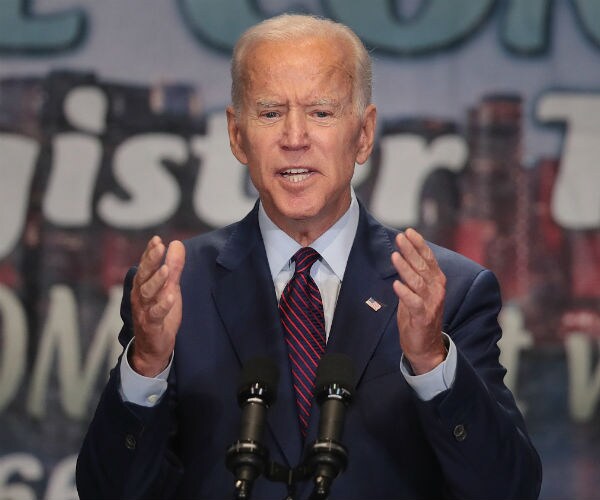 biden raises his arms as he makes a speech