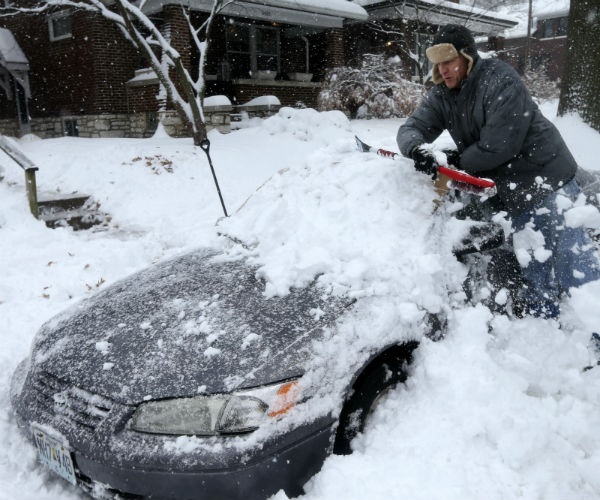 a man shovels snow off a car