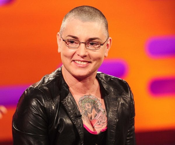 sinead o'connor at an event in black with chest tattoo visible above neckline of shirt