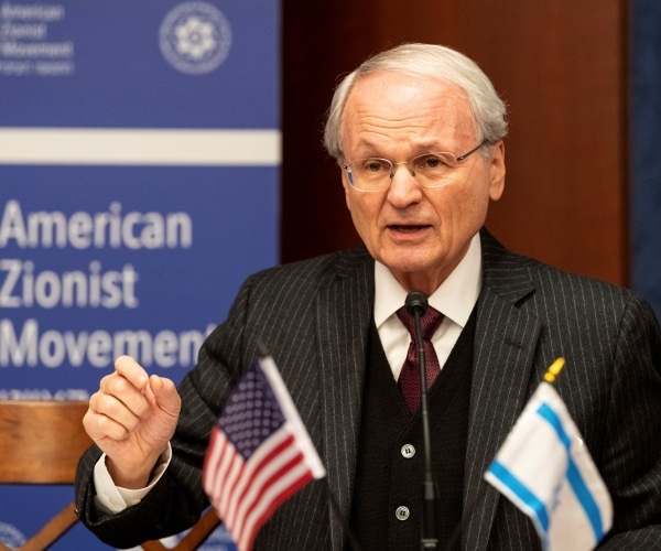 klein in a striped suit with israeli and us flags in the foreground