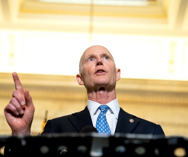 rick scott speaks from behind podium