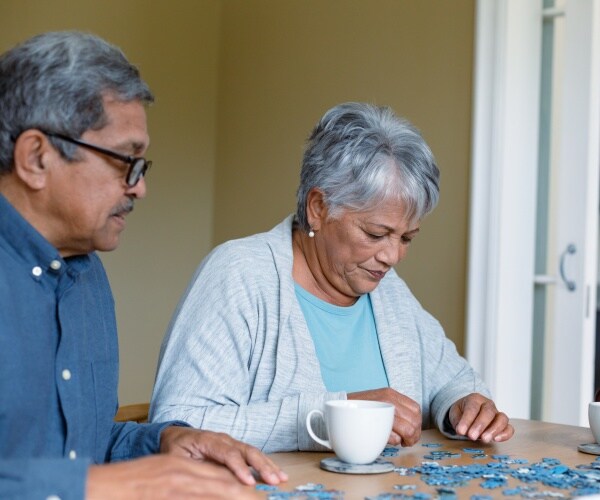 older man and woman doing a puzzle at table