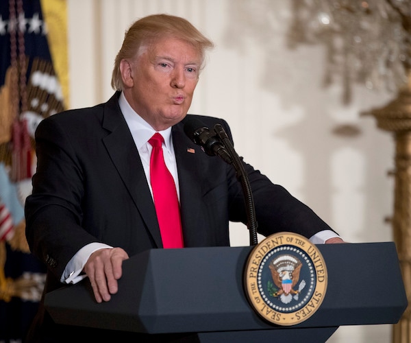 president donald trump grips both sides of the podium with each hand as he stands with a look of bewilderment