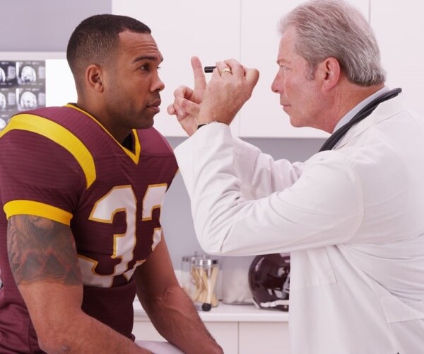 doctor examining football player for concussion