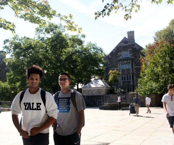 yale university students walking on campus in front of a building near trees